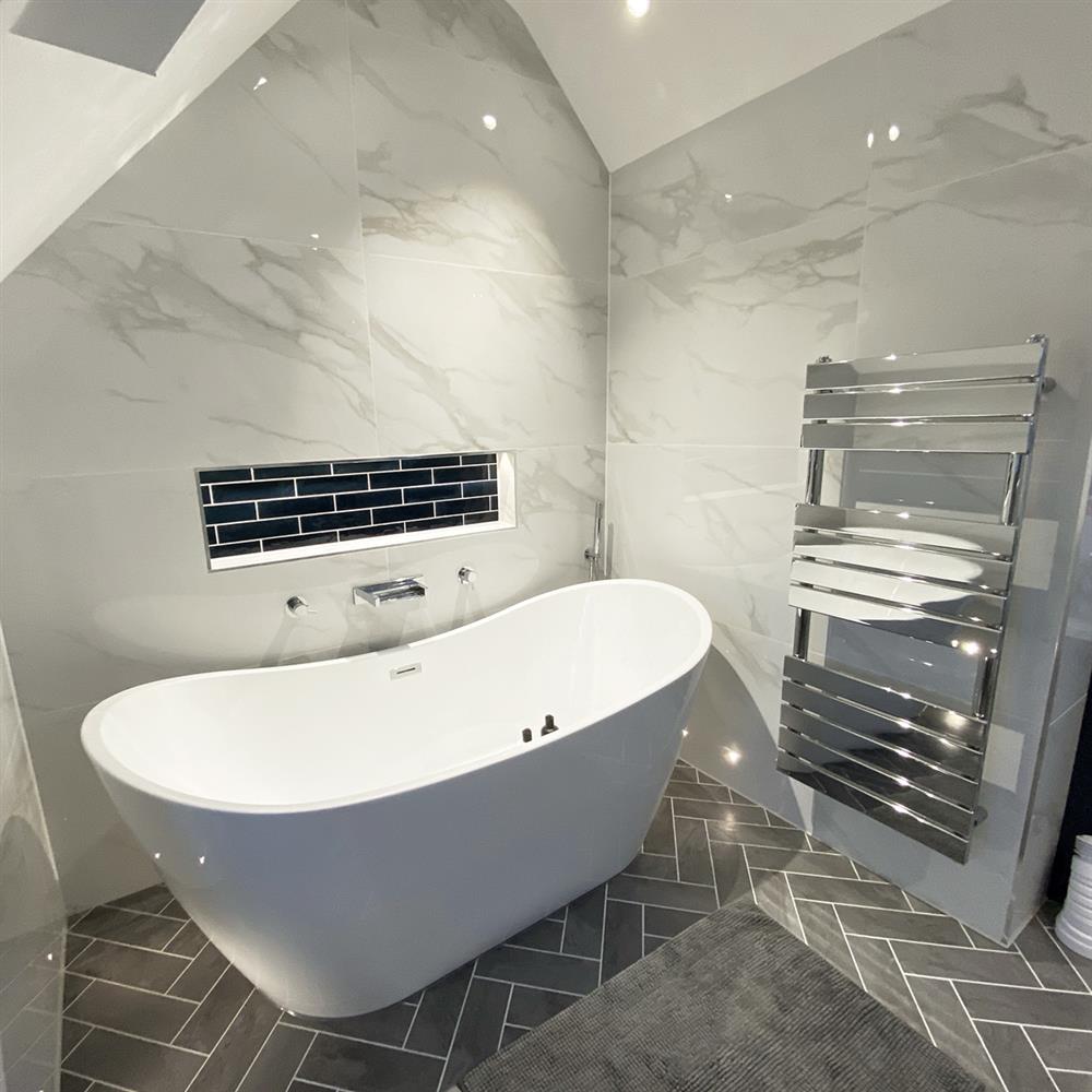 Modern bathroom with herringbone grey floor tiles and polished white marble wall tiles